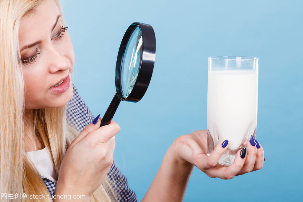 女人看着牛奶通过放大镜